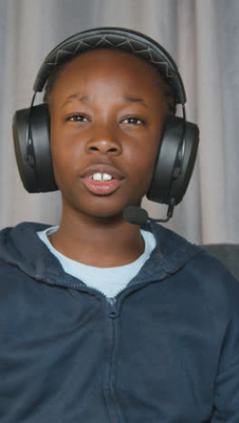 Vertical-Video-Of-Boy-At-Home-Sitting-On-Sofa-Wearing-Headset-Playing-Video-Game